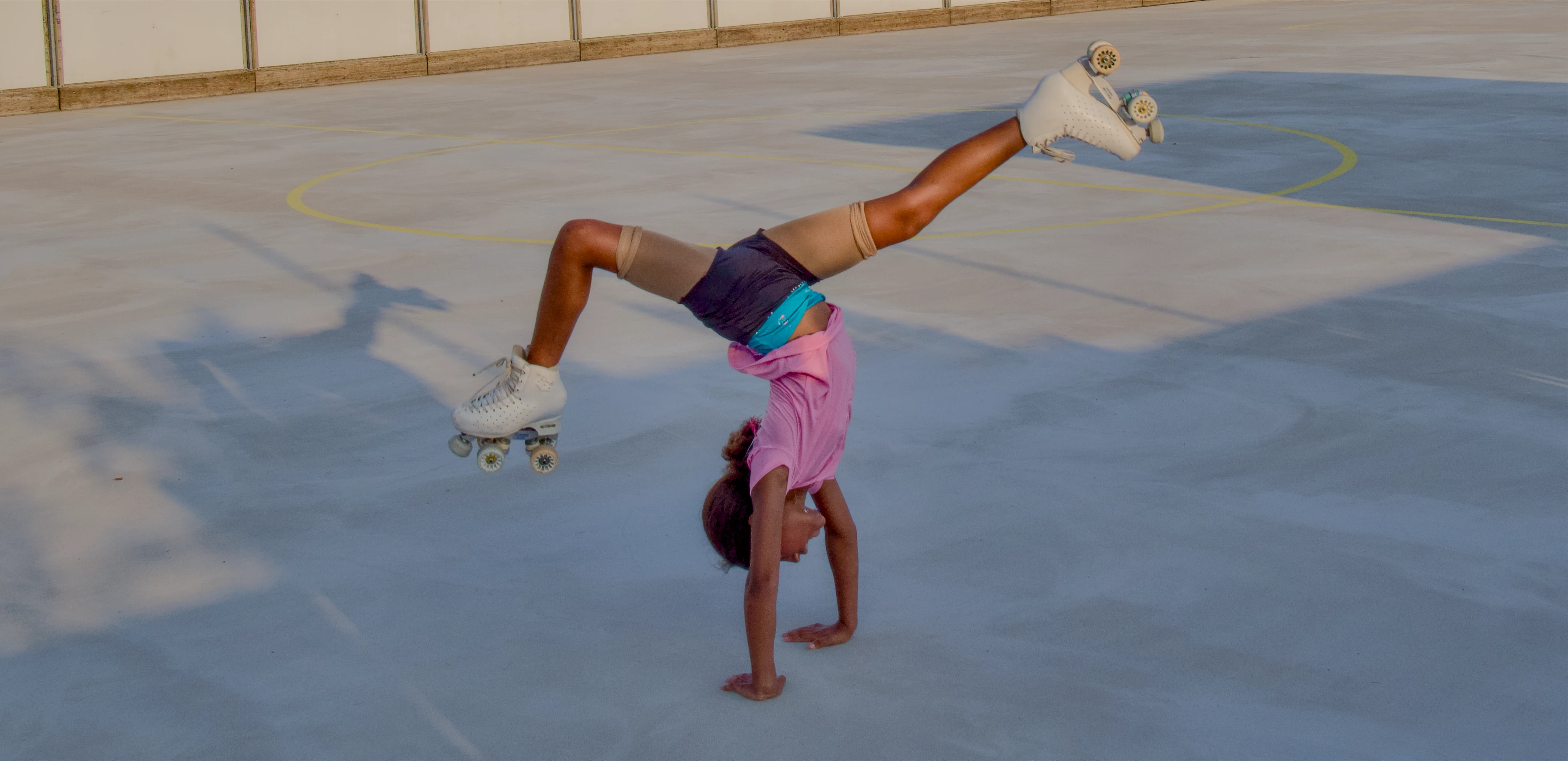 Une jeune patineuse réalise une figure acrobatique sur la piste extérieure