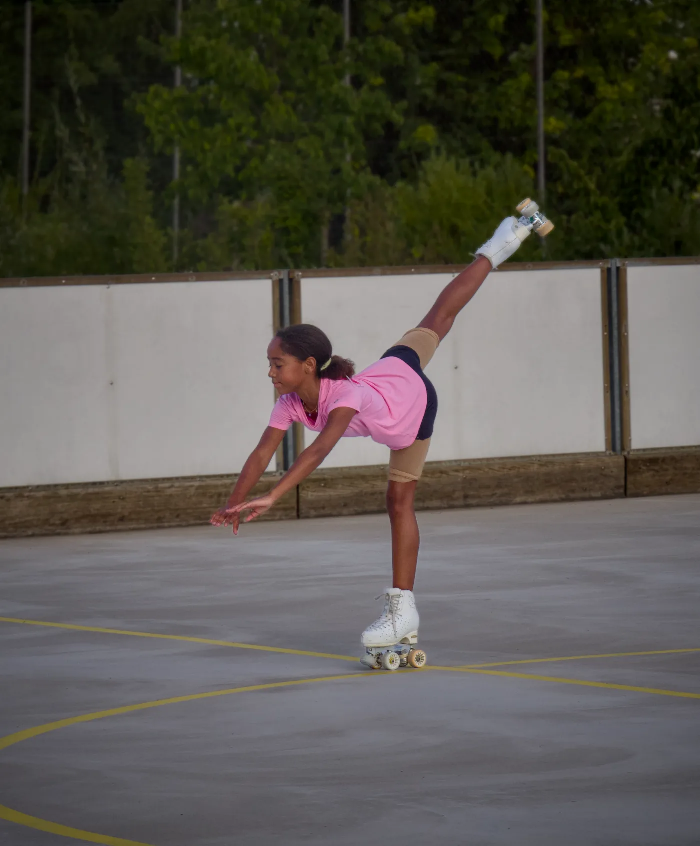 Une jeune patineuse réalise une arabesque sur la piste extérieure