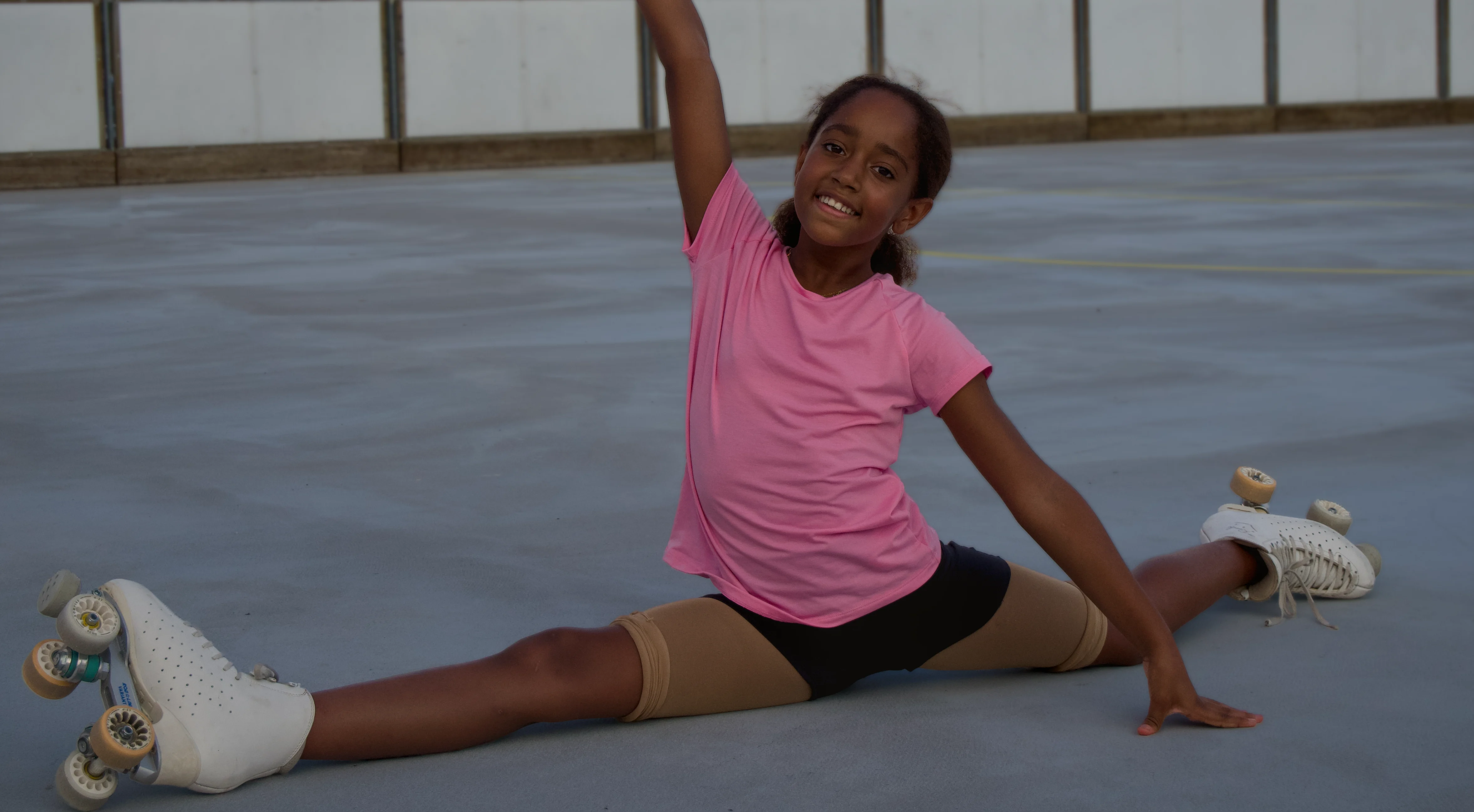 Une jeune patineuse souriante réalise un grand écart sur la piste